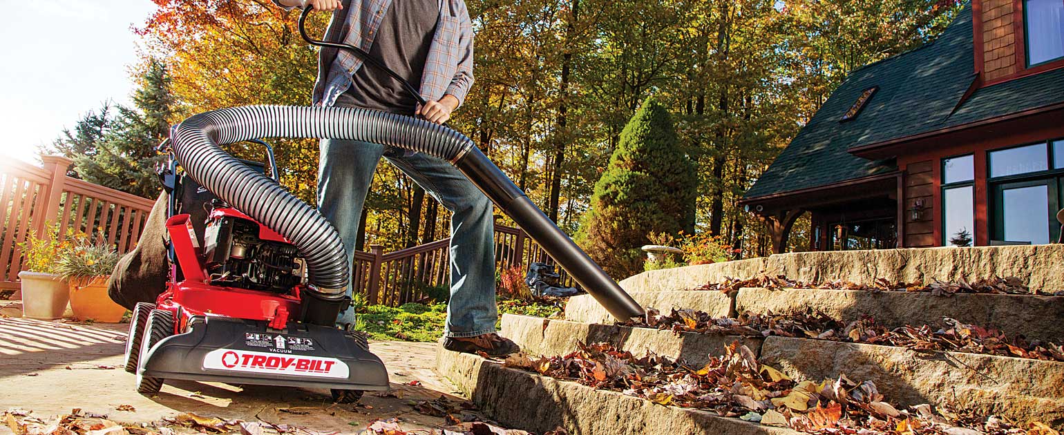Man shredding tree leaves with a Troy-Bilt Chipper Shredder Vacuum
