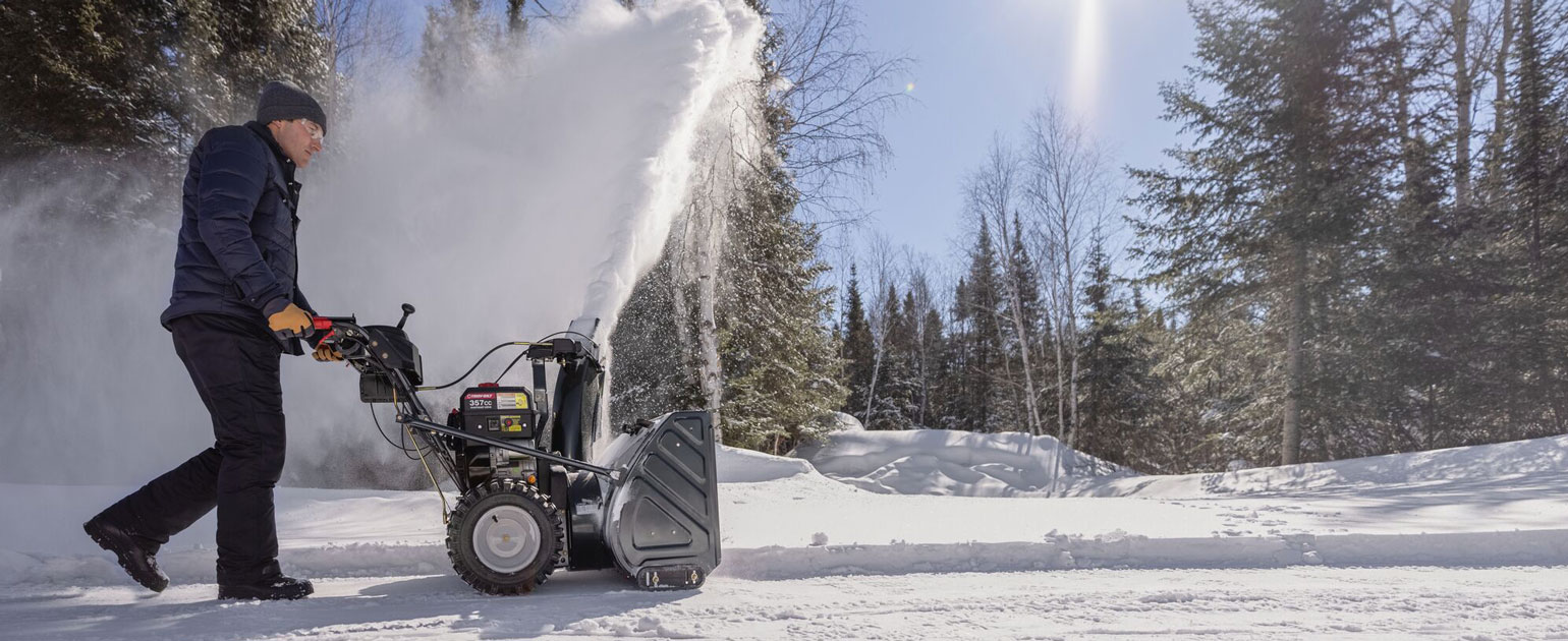 troy-bilt snow blower being operated on a driveway
