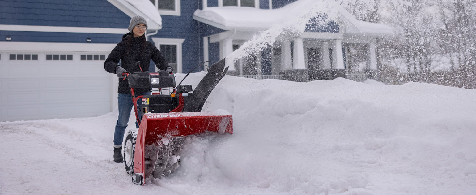 troy-bilt snow blower being operated on a driveway